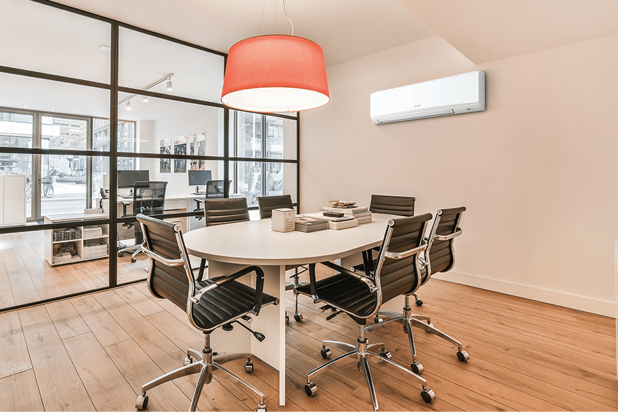 Mitsubishi Electric PKA-M71/100KAL3 commercial wall mounted air conditioner installed in a modern office meeting room with round table and chairs.