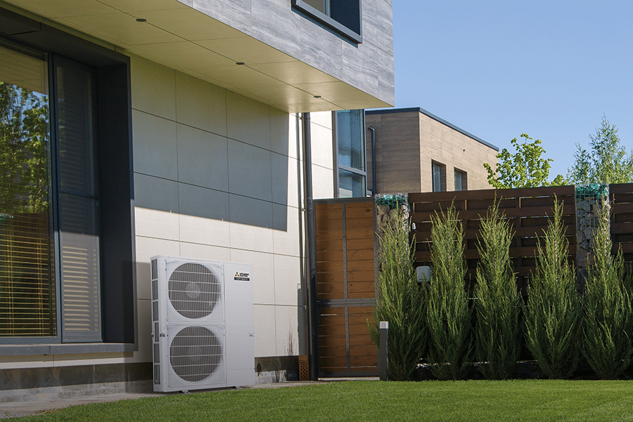 Mitsubishi Electric PUMY-P outdoor unit installed on the side wall of a modern home, demonstrating flexible placement options for residential or commercial air conditioning systems.